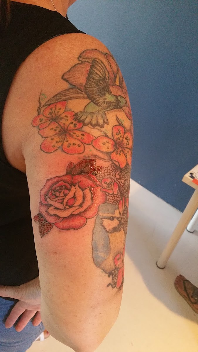 Botanische tattoo met rozen en bloemen op de bovenarm, fijne lijn met kleur
